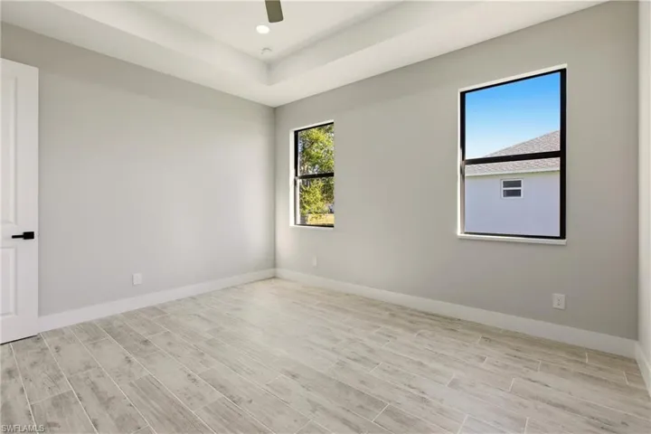 Bedroom with wood finish floors, recessed lighting, a raised ceiling, and a ceiling fan