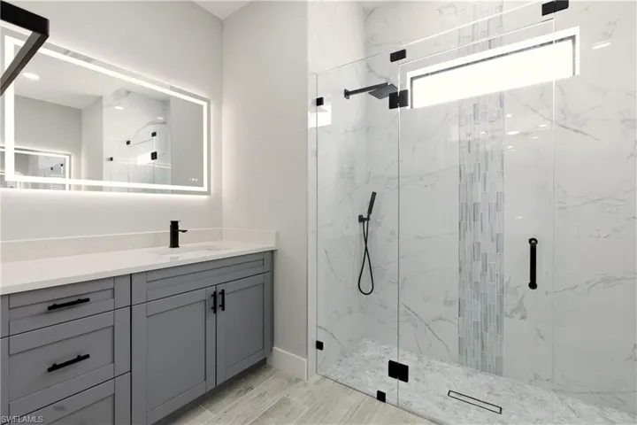 Bathroom featuring vanity and a marble finish shower