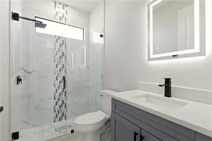 Bathroom featuring vanity and a marble finish shower