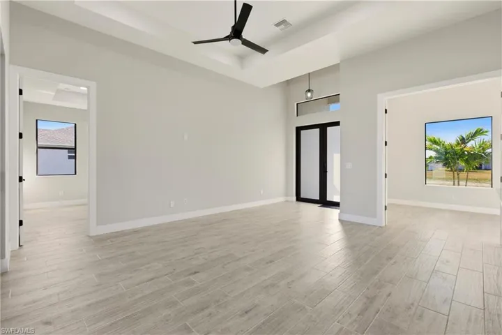 Foyer featuring plenty of natural light, a tray ceiling, wood finish floors, and a high ceiling. Office bonus room shown to the right.