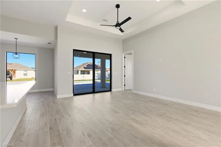 Living/kitchen area with wood tiled floors, a tray ceiling, a ceiling fan, and recessed lighting