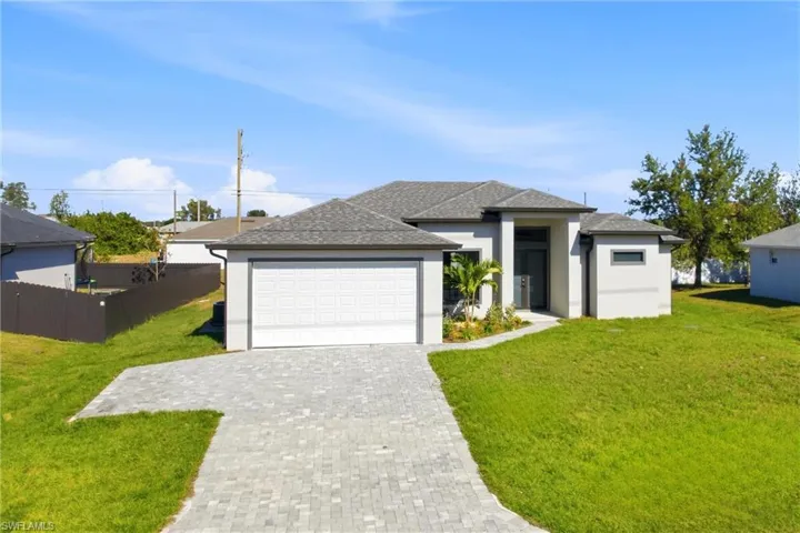 View of front facade featuring stucco siding, roof with shingles, decorative driveway, and an attached garage