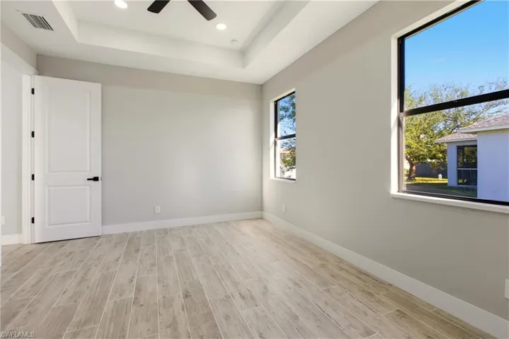 Bedroom featuring wood finish floors, a tray ceiling, recessed lighting, and a ceiling fan
