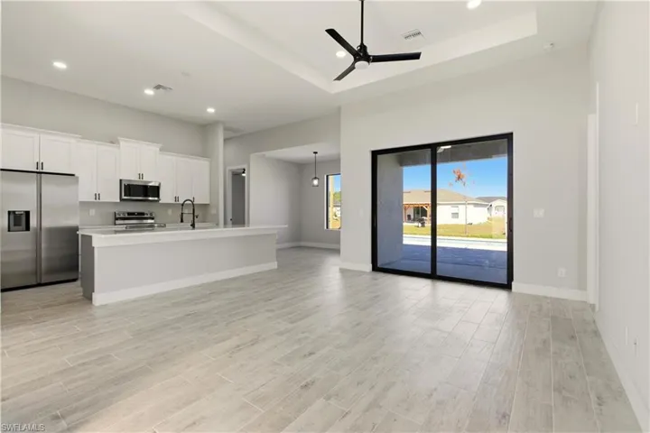 Living room featuring wood tiled floors, recessed lighting, ceiling fan, and a raised ceiling
