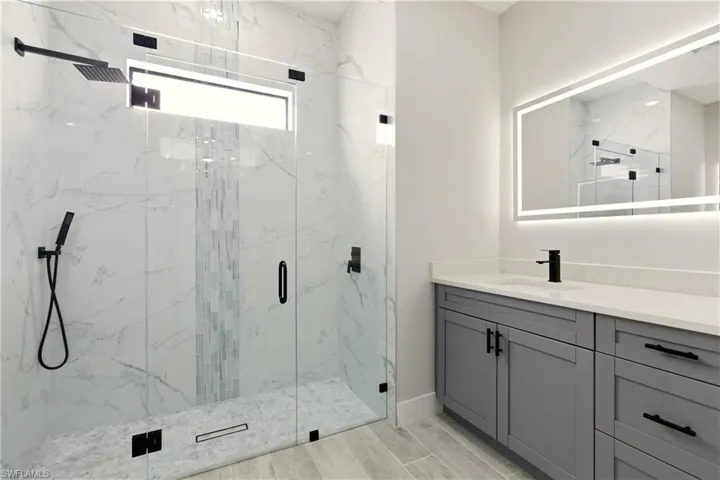 Bathroom with vanity, a marble finish shower, and wood tiled floors