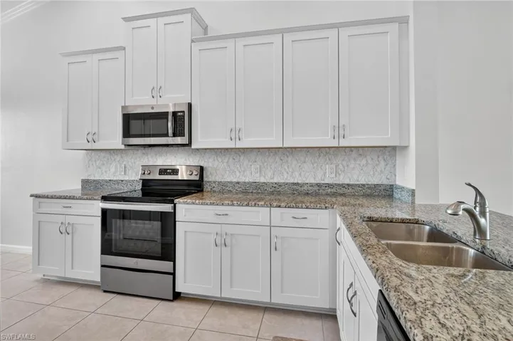 Kitchen featuring stainless steel appliances, light tile patterned floors, and backsplash