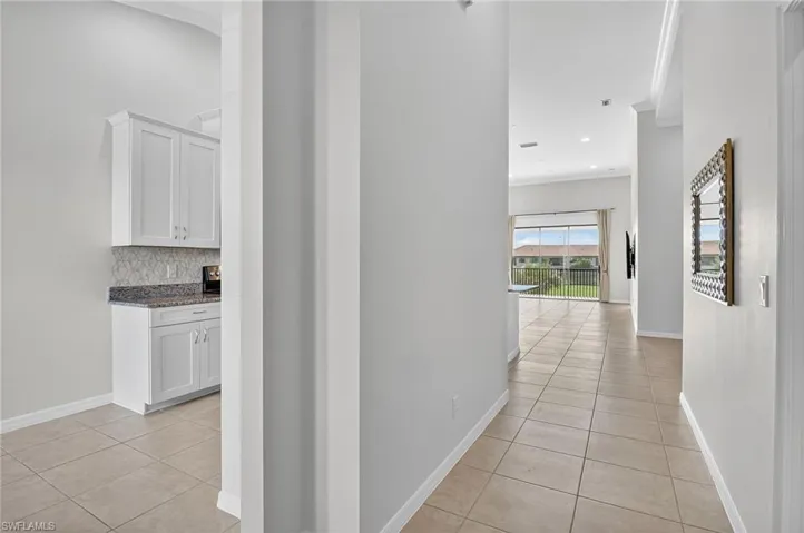 Corridor featuring light tile patterned flooring and ornamental molding