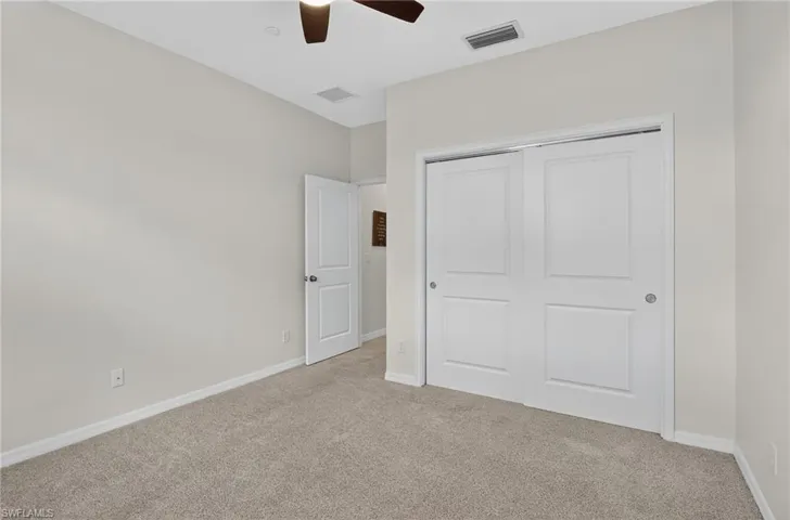 Unfurnished bedroom with light colored carpet, a closet, and a ceiling fan