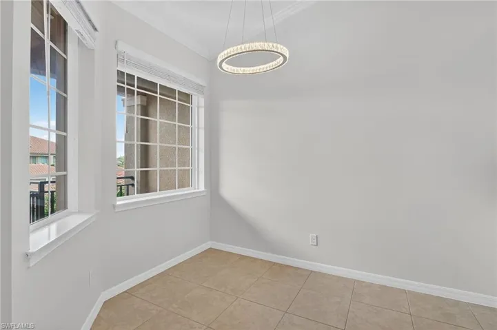 Tiled empty room featuring a chandelier and ornamental molding