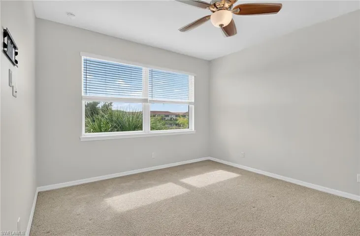 Carpeted empty room with baseboards and a ceiling fan
