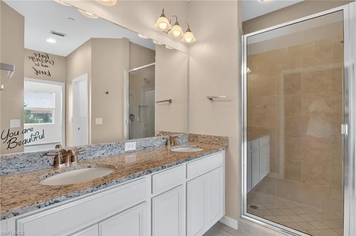 Full bath with a shower stall, double vanity, and tile patterned flooring