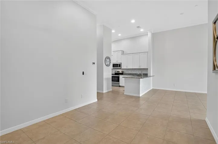 Unfurnished living room featuring ornamental molding, light tile patterned floors, recessed lighting, and a high ceiling