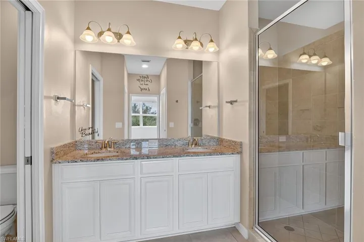 Bathroom with double vanity, a shower stall, and tile patterned flooring