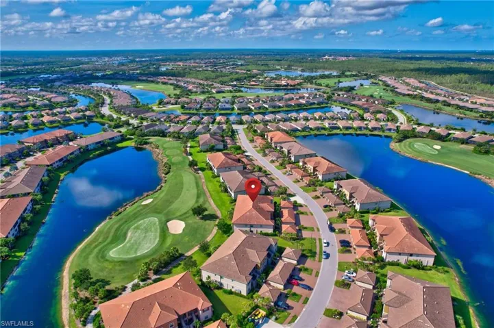 Aerial overview of property's location with nearby suburban area, a golf course, and a large body of water