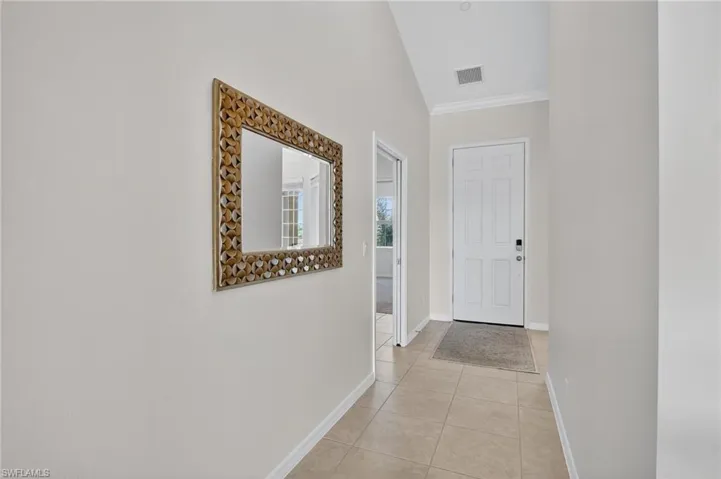 Corridor with crown molding and light tile patterned flooring
