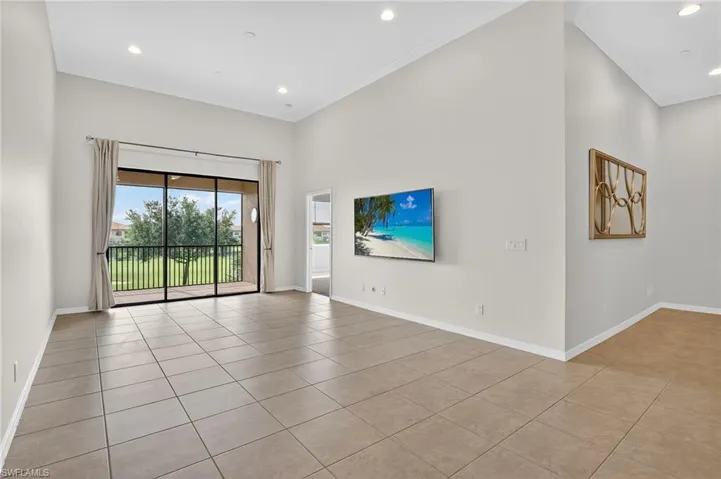 Unfurnished living room with light tile patterned flooring, crown molding, recessed lighting, and a high ceiling