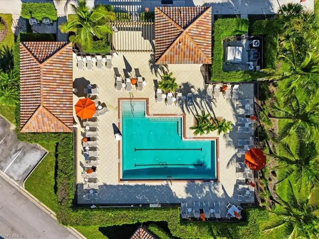 In-ground lap pool featuring a tiled deck, covered pergola, terracotta-tiled roof structures, and landscaped perimeter