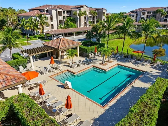 Community swimming pool featuring a lap lane, tiled pool deck, pergola-covered lounge area, and landscaping