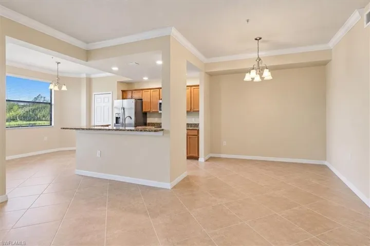 Ceramic tile flooring, crown molding, kitchen with stone-finish countertops, and dual hanging light fixtures