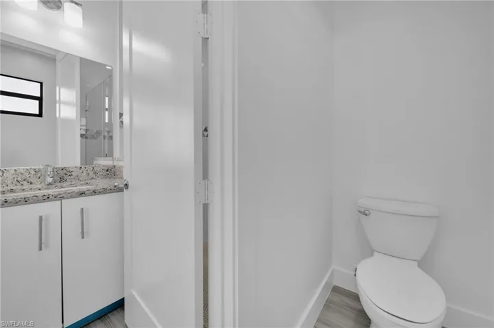 White vanity with a speckled countertop, undermount sink, and contemporary light fixture