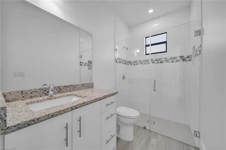 White vanity with stone-finish countertop, integrated sink, and chrome faucet