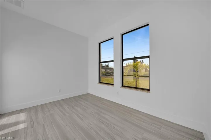 Wood-finish flooring, white wall finishes, and two windows with black frames
