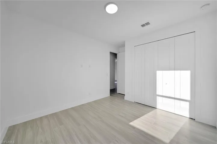 Wood-finish flooring with white baseboards, a flush-mount ceiling light, and white bi-fold closet doors