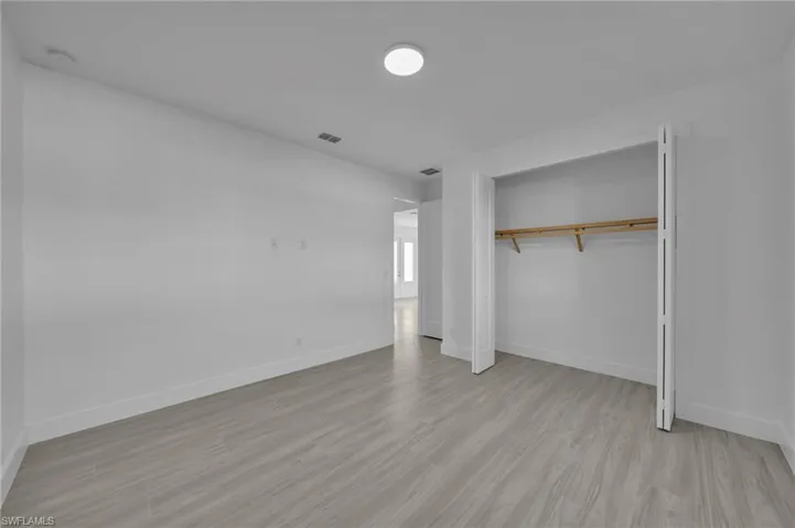 Recessed ceiling light, light wood-finish flooring, and built-in closet with shelving