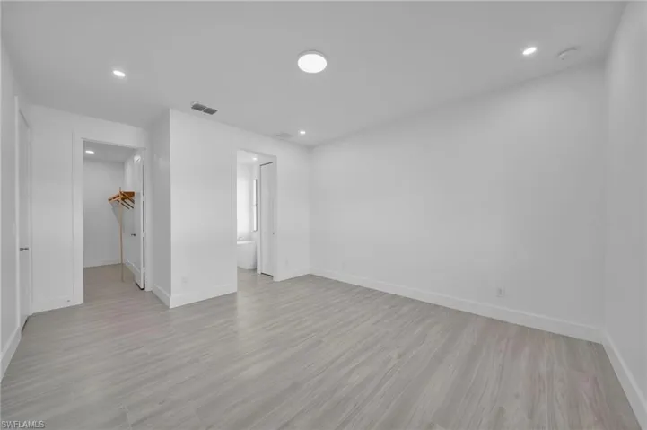 Spacious room featuring light wood-finish flooring, recessed lighting, and a neutral wall palette
