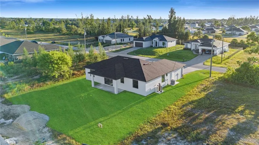 Contemporary single-story residence with a dark shingle roof, white exterior walls, and a covered rear patio