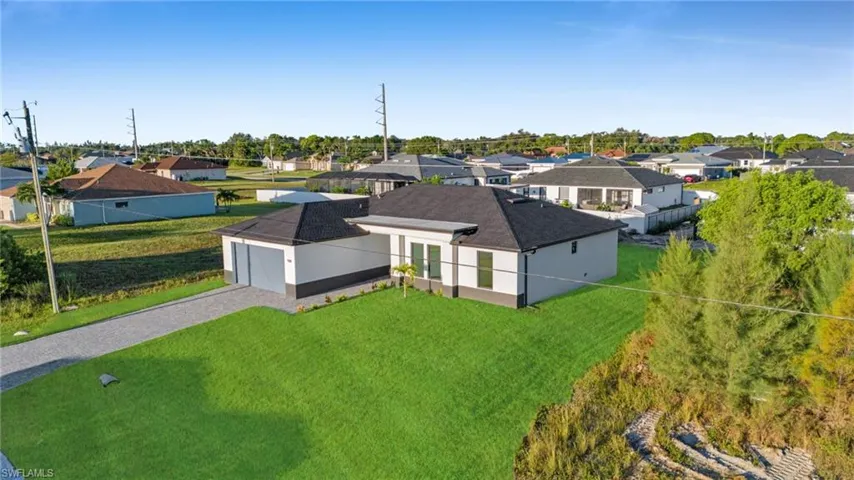 Contemporary exterior with a dark-pitched roof, attached garage, and a manicured front lawn