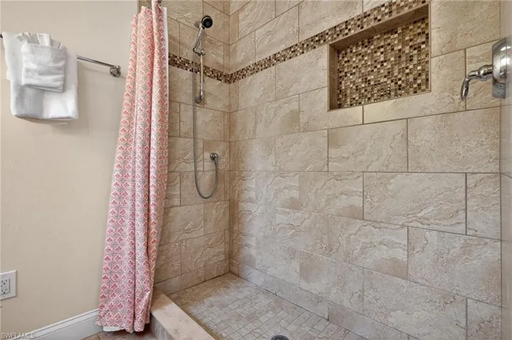 Bathroom with a shower stall and baseboards