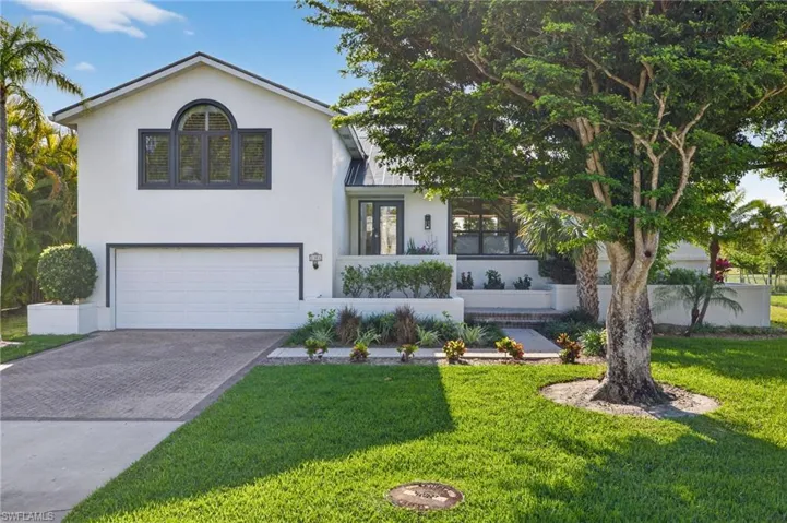 Tri-level home with decorative driveway, a garage, stucco siding, and a front yard