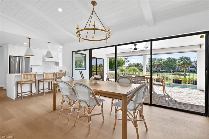 Dining room featuring light wood finished floors, ceiling fan, a chandelier, and lofted ceiling with beams
