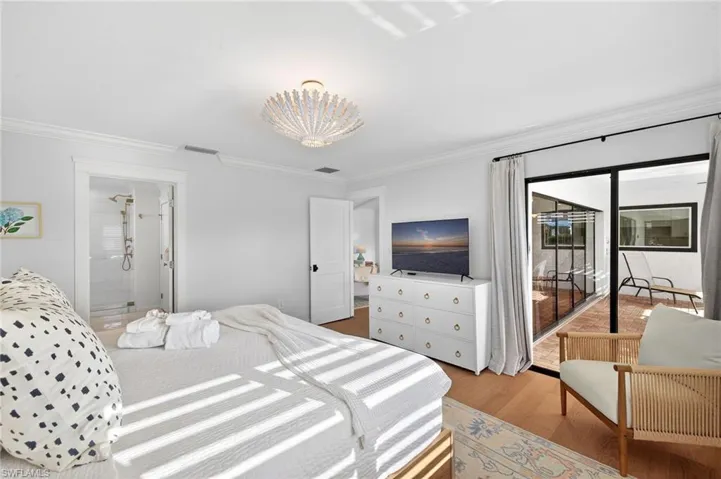 Primary Bedroom with crown molding, access to exterior, light wood finished floors, and ensuite bath