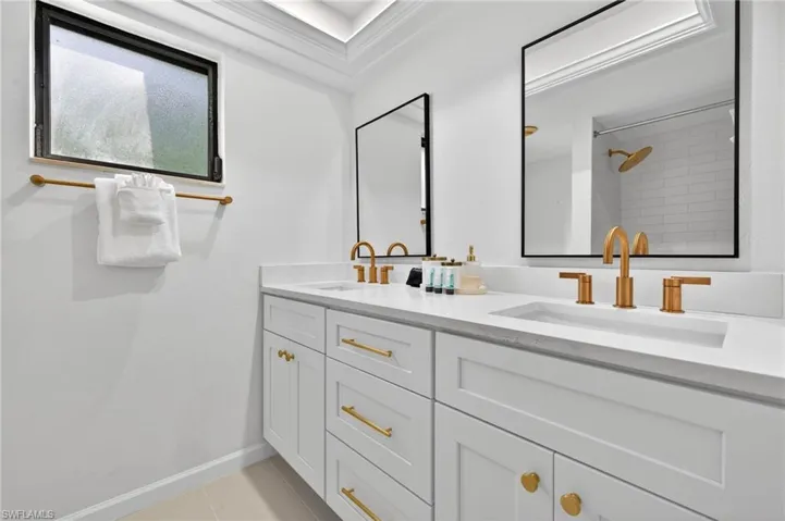Full bath featuring double vanity, ornamental molding, and light tile patterned floors
