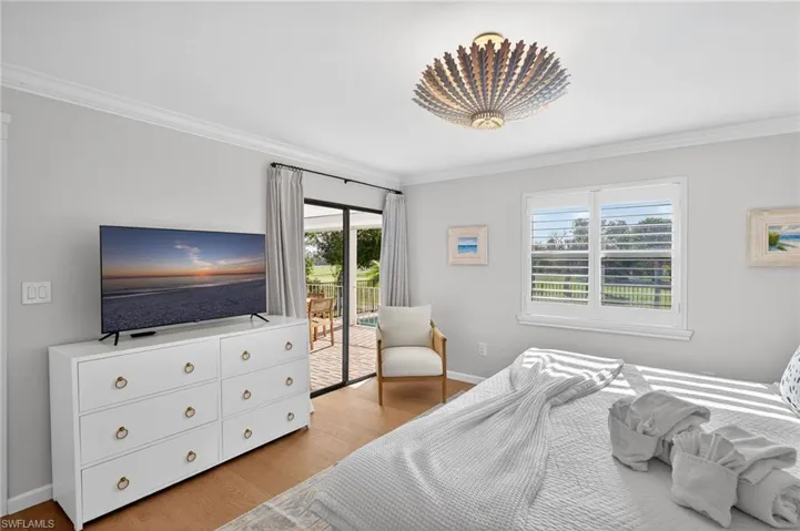Primary Bedroom with light wood-style floors, access to outside, and crown molding