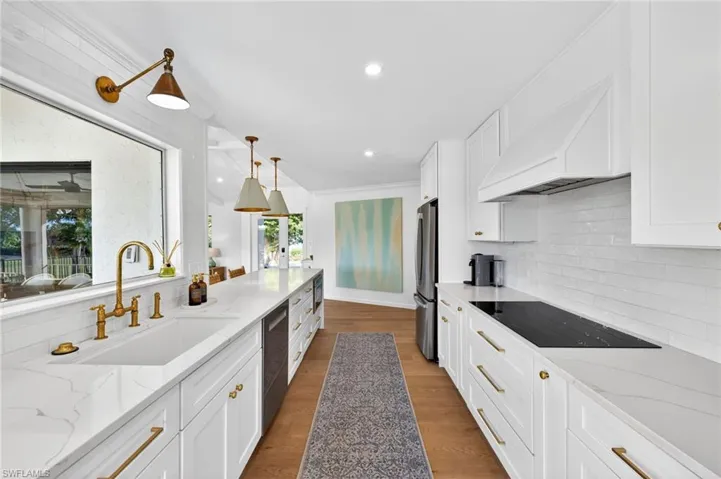 Kitchen with light stone countertops, white cabinets, dark wood finished floors, stainless steel appliances, and tasteful backsplash