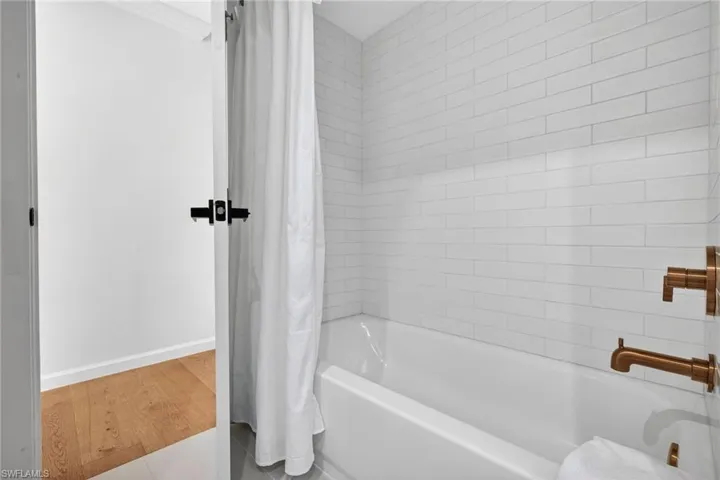 Full bathroom with shower / bathtub combination with curtain and light wood-type flooring