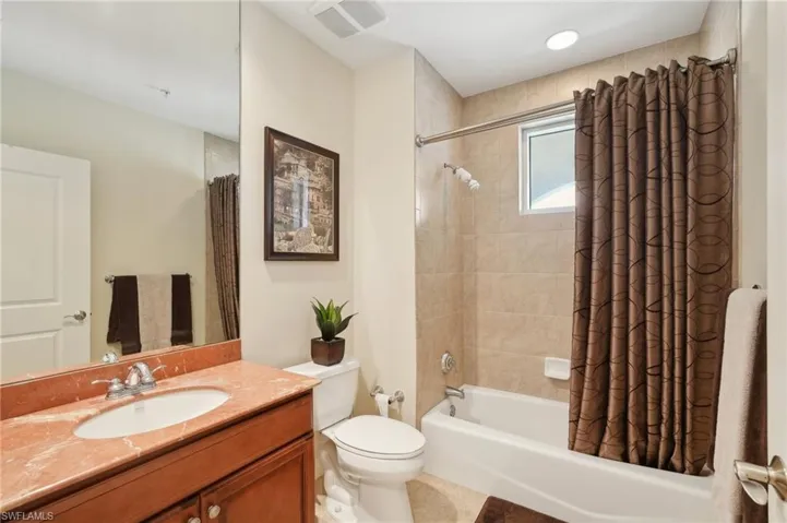Full bathroom featuring toilet, vanity, shower / tub combo with curtain, and visible vents