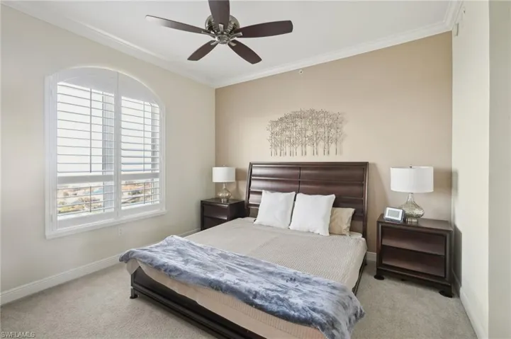 Carpeted bedroom featuring a ceiling fan, crown molding, and baseboards