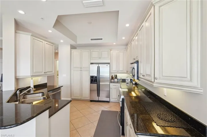 Kitchen featuring a sink, stainless steel appliances, a tray ceiling, and visible vents