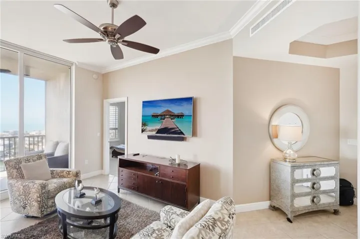 Living area with ornamental molding, baseboards, ceiling fan, and visible vents