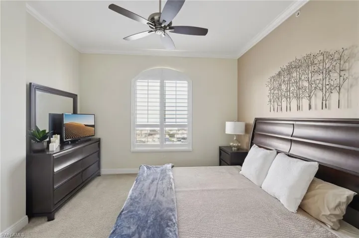 Bedroom with baseboards, carpet floors, ornamental molding, and ceiling fan