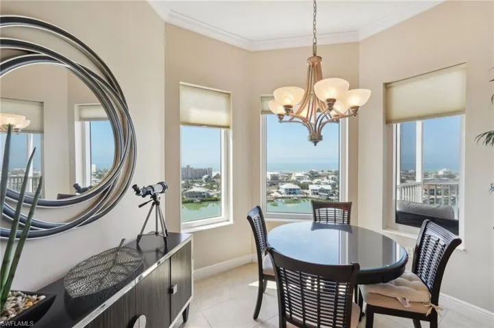 Dining space featuring crown molding, baseboards, a chandelier, and a city view