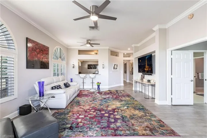 Living area with crown molding, ceiling fan, and light wood-type flooring