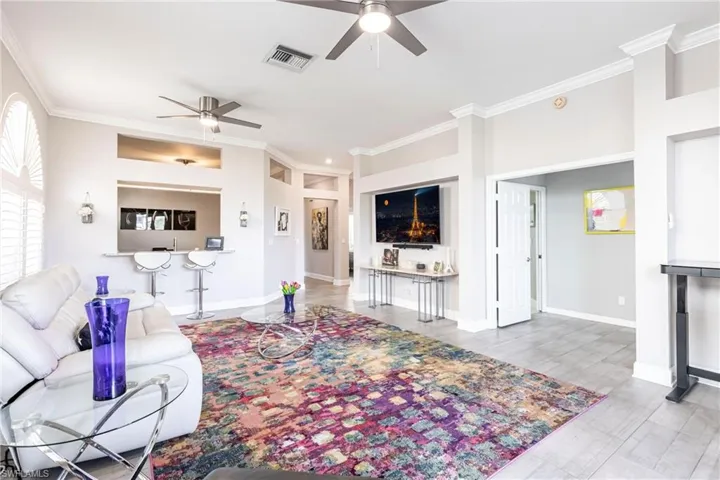 Living area featuring ornamental molding, ceiling fan, and light wood finished floors