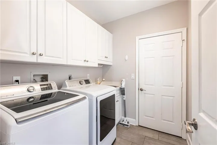 Washroom featuring washing machine and dryer, cabinet space, and light wood-type flooring