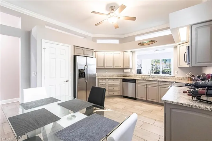 Kitchen featuring appliances with stainless steel finishes, ornamental molding, light stone countertops, gray cabinetry, and a ceiling fan