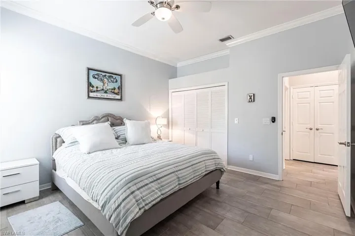 Bedroom with ornamental molding, light wood-type flooring, a ceiling fan, and a closet